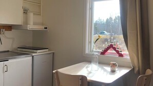 A small kitchen with white cabinets, a white table, and two chairs. - Ölrun Stuga (Hammarstrand)