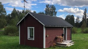 A small red wooden cabin with a sloped roof, a single window, and a door. - Ölrun Stuga (Hammarstrand)