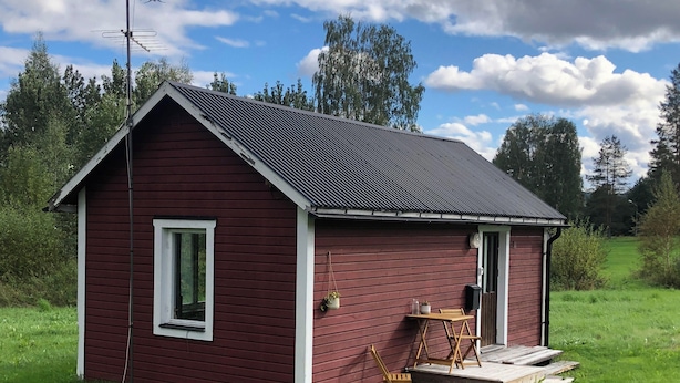 A small, single-story red wooden cabin with a metal roof, a window, and a door. - Ölrun Stuga (Hammarstrand)