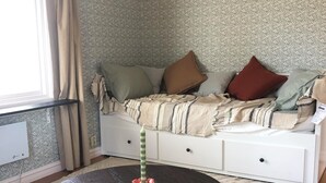 A cozy room with a sofa bed, a round table, and a patterned rug. - Ölrun Stuga (Hammarstrand)