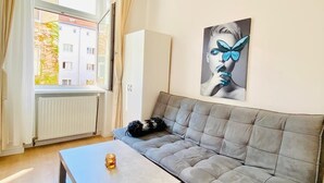 Un salon moderne avec un canapé gris, une petite table et une fenêtre avec des rideaux.