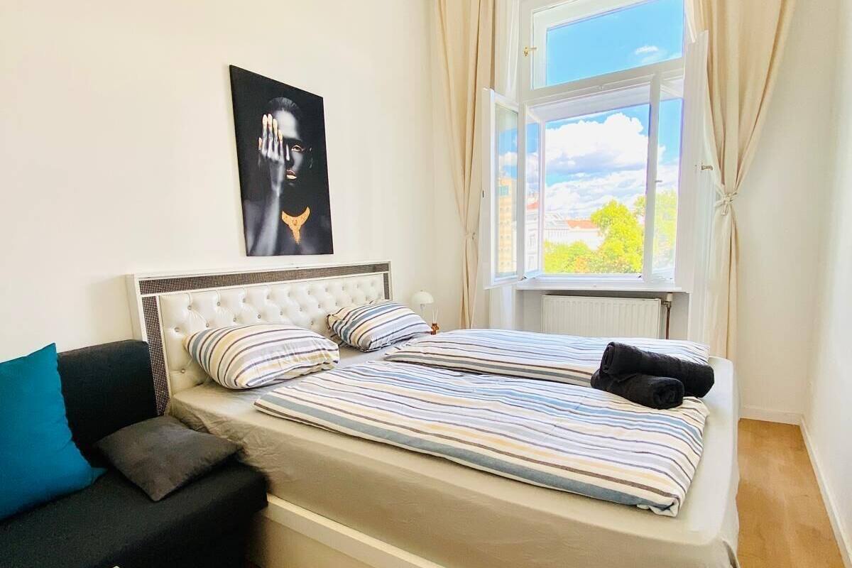 Een slaapkamer met een bed, een bank, een raam met gordijnen en een poster aan de muur.