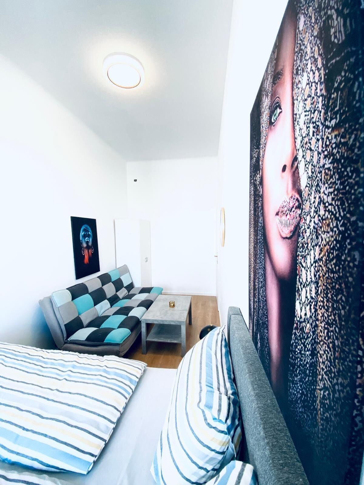 A modern bedroom with a sofa, a small table, and a large abstract painting.