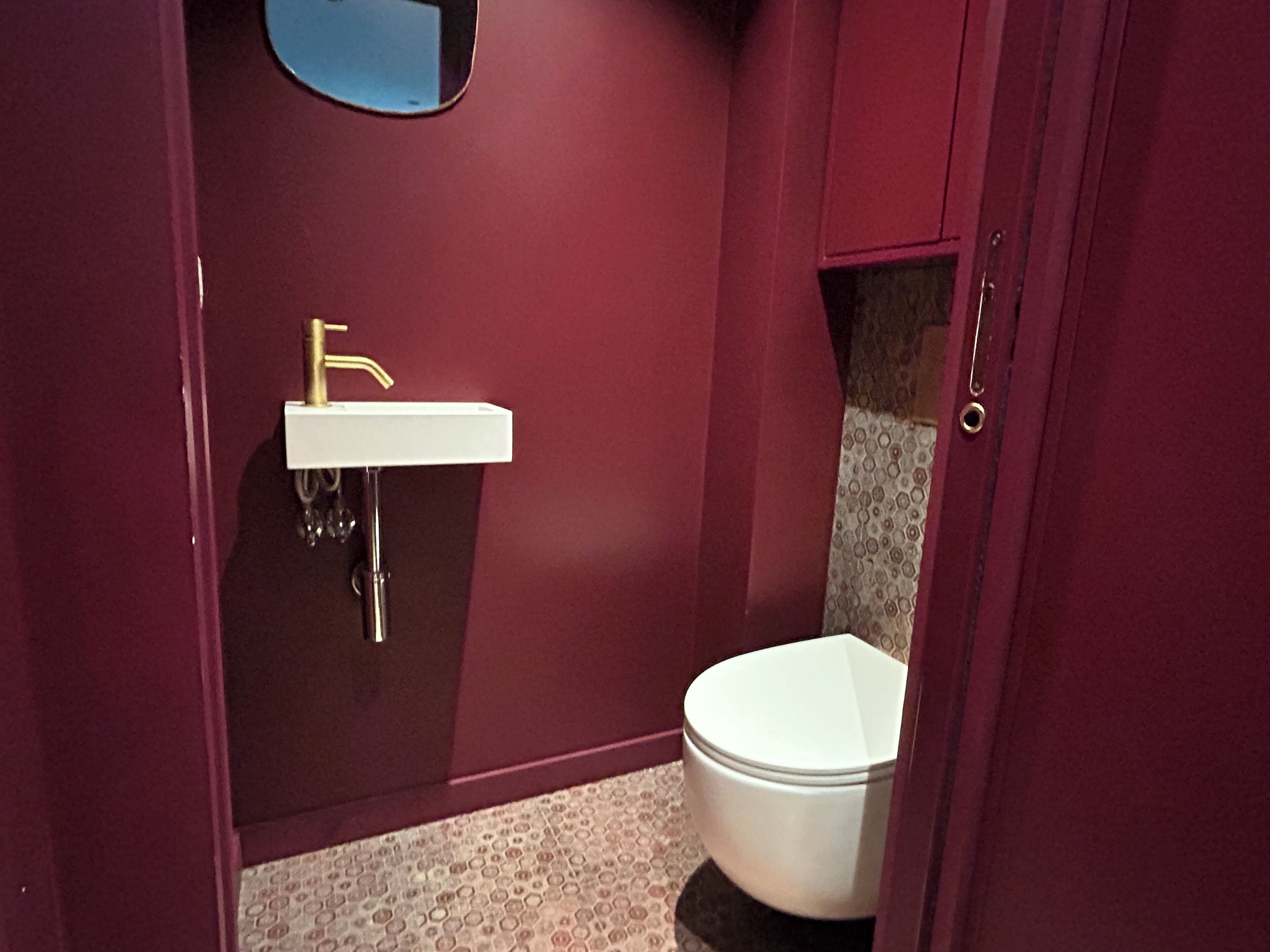 Une salle de bain avec un lavabo blanc, un robinet doré et des toilettes blanches.