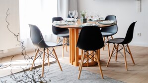 A dining area with a round table, black chairs, and a large pendant light.