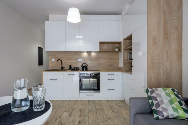 Een moderne keuken met witte kasten, een inbouwoven en een houten aanrecht.