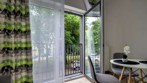 Een moderne kamer met een grote schuifpui naar een balkon, een eettafel met stoelen en een potorkidee op de tafel.