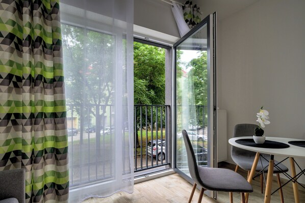 Een moderne kamer met een grote schuifpui naar een balkon, een eettafel met stoelen en een potorkidee op de tafel.