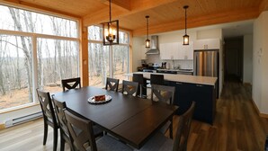 A modern kitchen with wooden ceiling, large windows, and a dining area with a table and chairs. - Lake, Spa & Game Room | Le Havre du Voyageur (La Minerve)