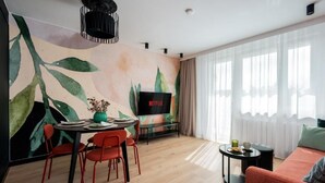 Een moderne woonkamer met een eethoek, een grote televisie en een bank.