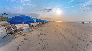Een strand met rijen blauwe parasols en ligbedden.