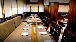 A restaurant with long tables set for dining, wooden paneling, and a large window.