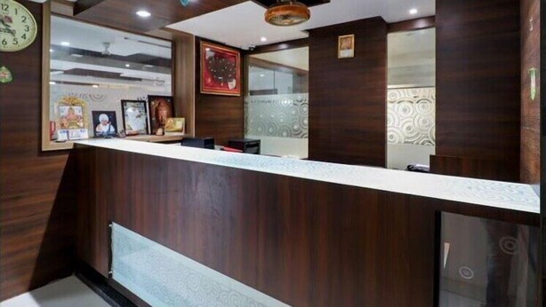 A reception area with a wooden reception desk, framed pictures on the wall, and a clock.