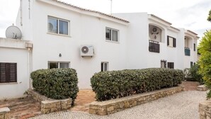 A white building with a tiled roof, stone steps, and a paved courtyard.