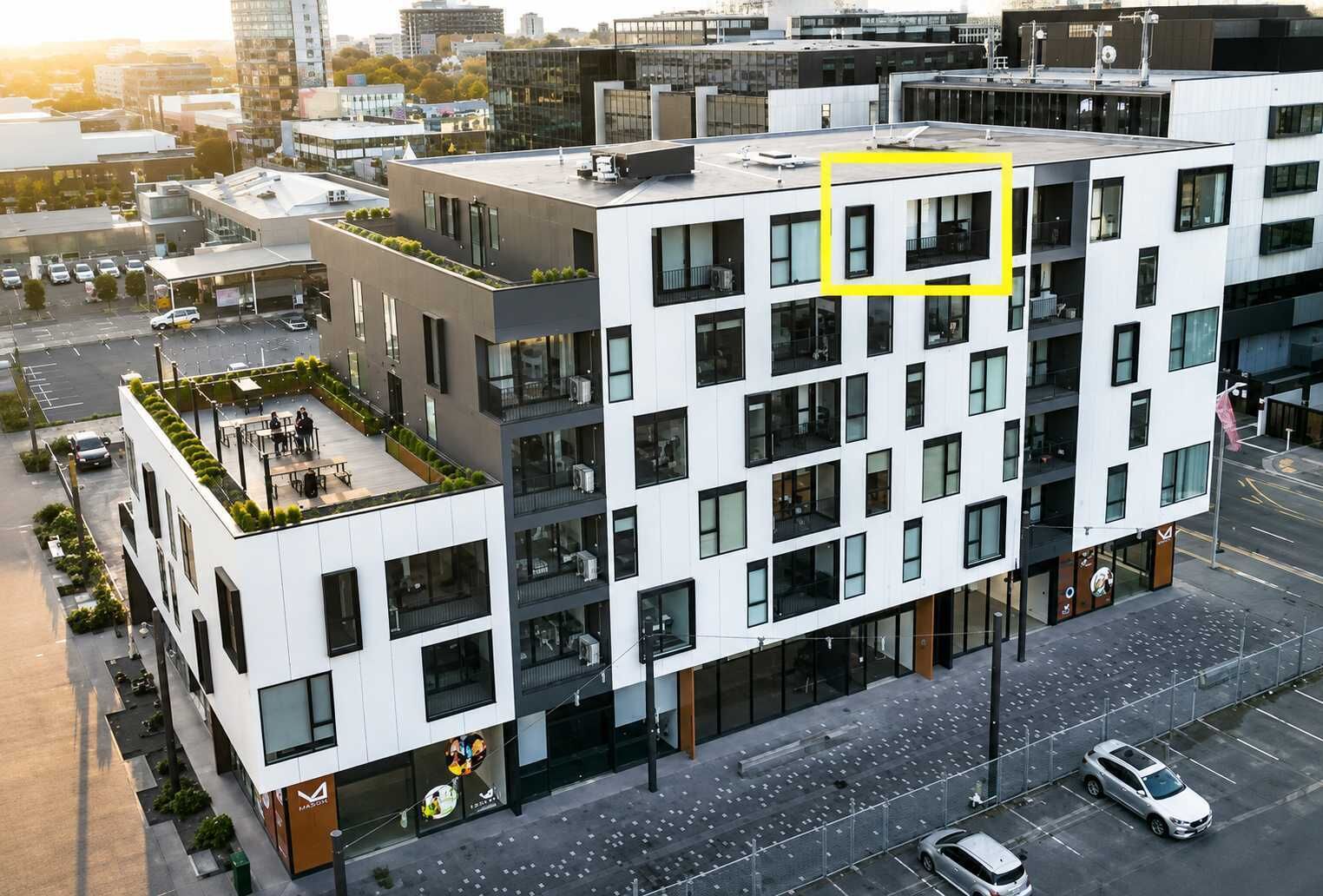 Un edificio de varios pisos con jardín en la azotea, ventanas grandes y acceso a nivel de calle.