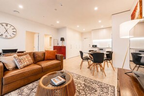 A modern living room with a leather sofa, a coffee table, and a dining area with chairs and a table.