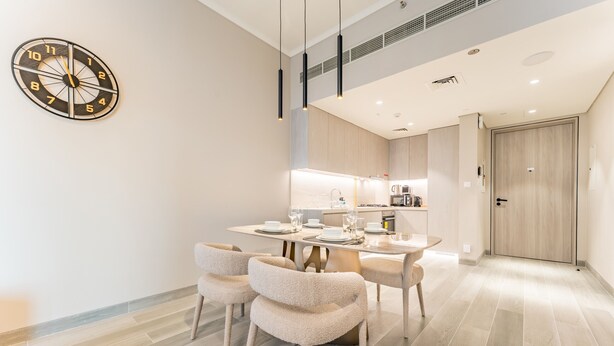 Un comedor moderno con una mesa redonda, cuatro sillas y un reloj de pared.