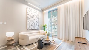 Una sala de estar moderna con un sofá blanco, una mesa de centro, una lámpara de pie y un cuadro abstracto grande en la pared.