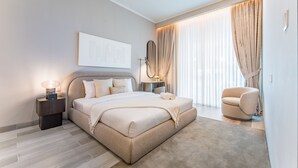 Un dormitorio moderno con una cama grande, mesitas de noche, una silla y un ventanal con cortinas.