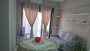 A living room with a dining table, a sofa, and a potted plant. - Apartment 204 (Messina)
