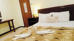 Une chambre d’hôtel avec un lit, une table de chevet en bois, un bureau et une porte.