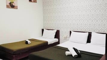 Habitación de hotel con dos camas individuales, una mesita y una obra de arte colgada en la pared.