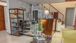 Un hall d’entrée avec un comptoir de réception, une vitrine contenant des en-cas, un petit sapin de Noël et un fauteuil jaune.