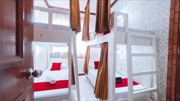 Una habitación con literas, paredes blancas y una puerta de madera.