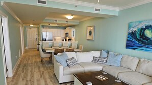 A modern living room with a beige sectional sofa, a wooden coffee table, and a patterned rug. - Holiday Isle SandDollar 713 (Dauphin Island)