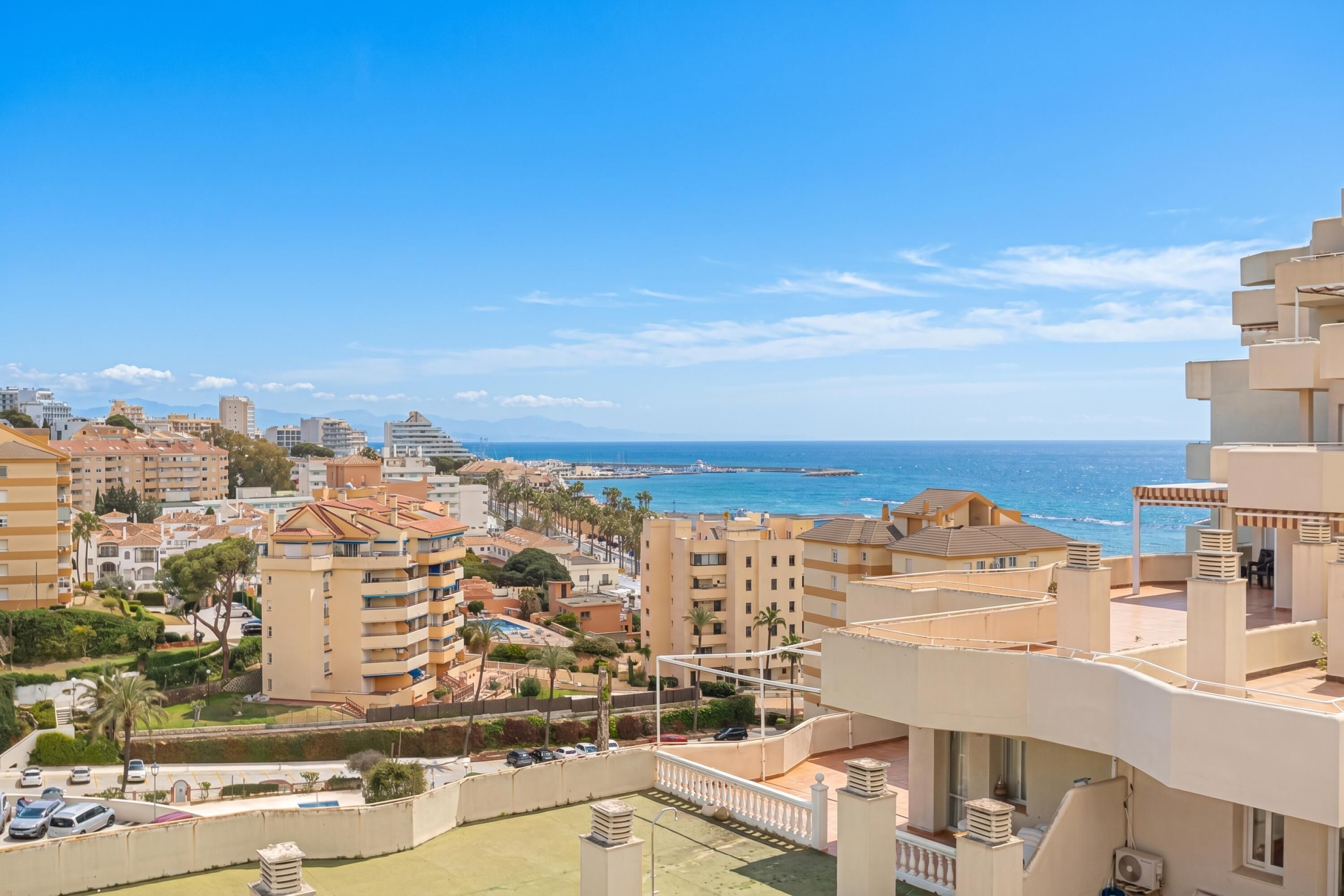 Un'area residenziale sulla costa, con edifici, cielo sereno e vista sul mare.