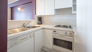 A compact kitchen with a sink, a coffee maker, a stove, and a dishwasher. - Apartment in Knokke Near Zeedijk Beach (Knokke-Heist)
