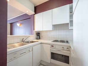 A compact kitchen with a sink, a coffee maker, a stove, and a dishwasher.