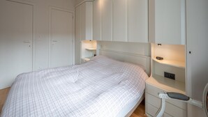 A bedroom with a bed, built-in wardrobe, bedside tables, and a nightstand. - Apartment in Knokke Near Zeedijk Beach (Knokke-Heist)
