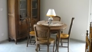 Un comedor con una mesa redonda, dos sillas, una lámpara y un armario de madera.