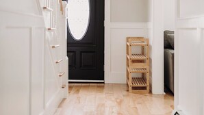 Un pasillo con una puerta negra, estanterías de madera y una escalera.
