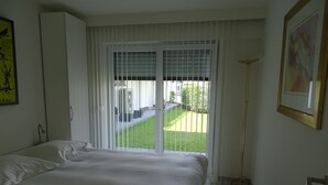 A bedroom with a bed, a window with blinds, a floor lamp, and a painting on the wall. - Relaxing Escape in Knokke (Knokke-Heist)