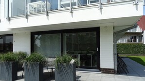 A modern building with large glass windows, a flat roof, and a paved entrance area with planters. - Relaxing Escape in Knokke (Knokke-Heist)