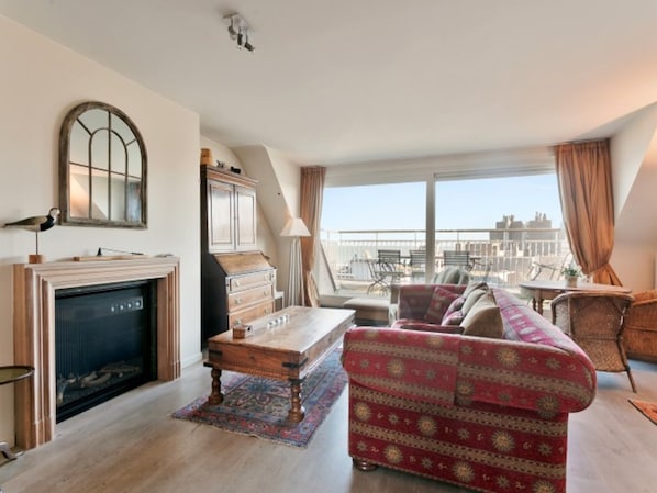 Una sala de estar con chimenea, un sofá, una mesa de centro y vistas de la ciudad.