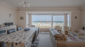 Une chambre d’hôtel équipée d’une table à manger, de chaises, d’un canapé et offrant une vue sur la plage.