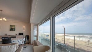 Une chambre d’hôtel moderne dotée d’un grand balcon, d’un coin repas et offrant une vue sur la plage et la mer.