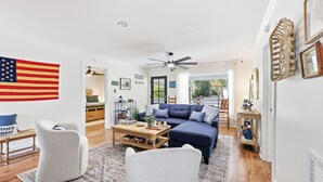 A living room with a blue sofa, two armchairs, a coffee table, and a flag on the wall. - Cedar Creek - Creek Front, Mainland, 3-bedroom (Pawleys Island)