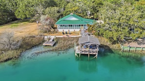 A house with a green roof, a dock, and a small boat. - Cedar Creek - Creek Front, Mainland, 3-bedroom (Pawleys Island)