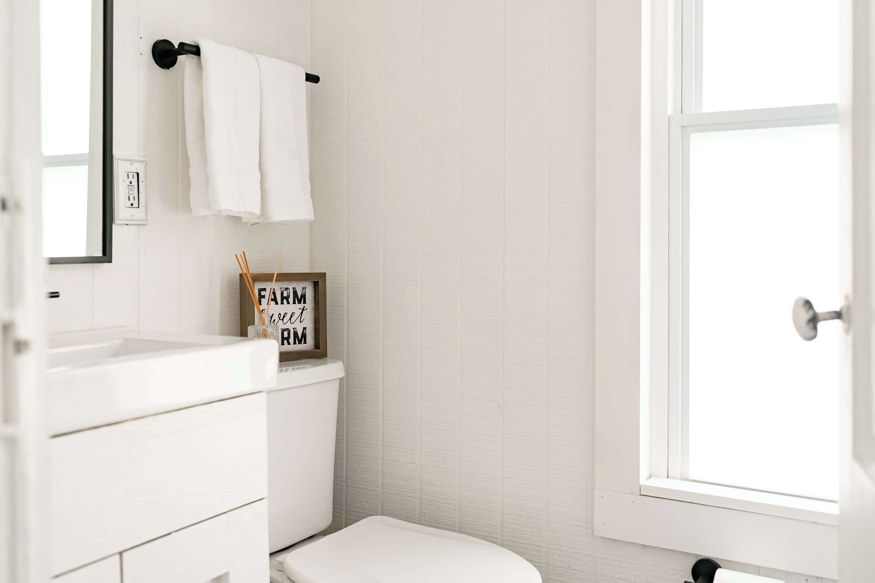 Een witte badkamer met toilet, wastafel en raam.