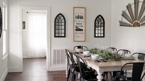 A dining area with a wooden table set for four, black chairs, and a decorative wall piece above the table. - Christmas Tree Farm - Evergreen Escape (Berrien Center)
