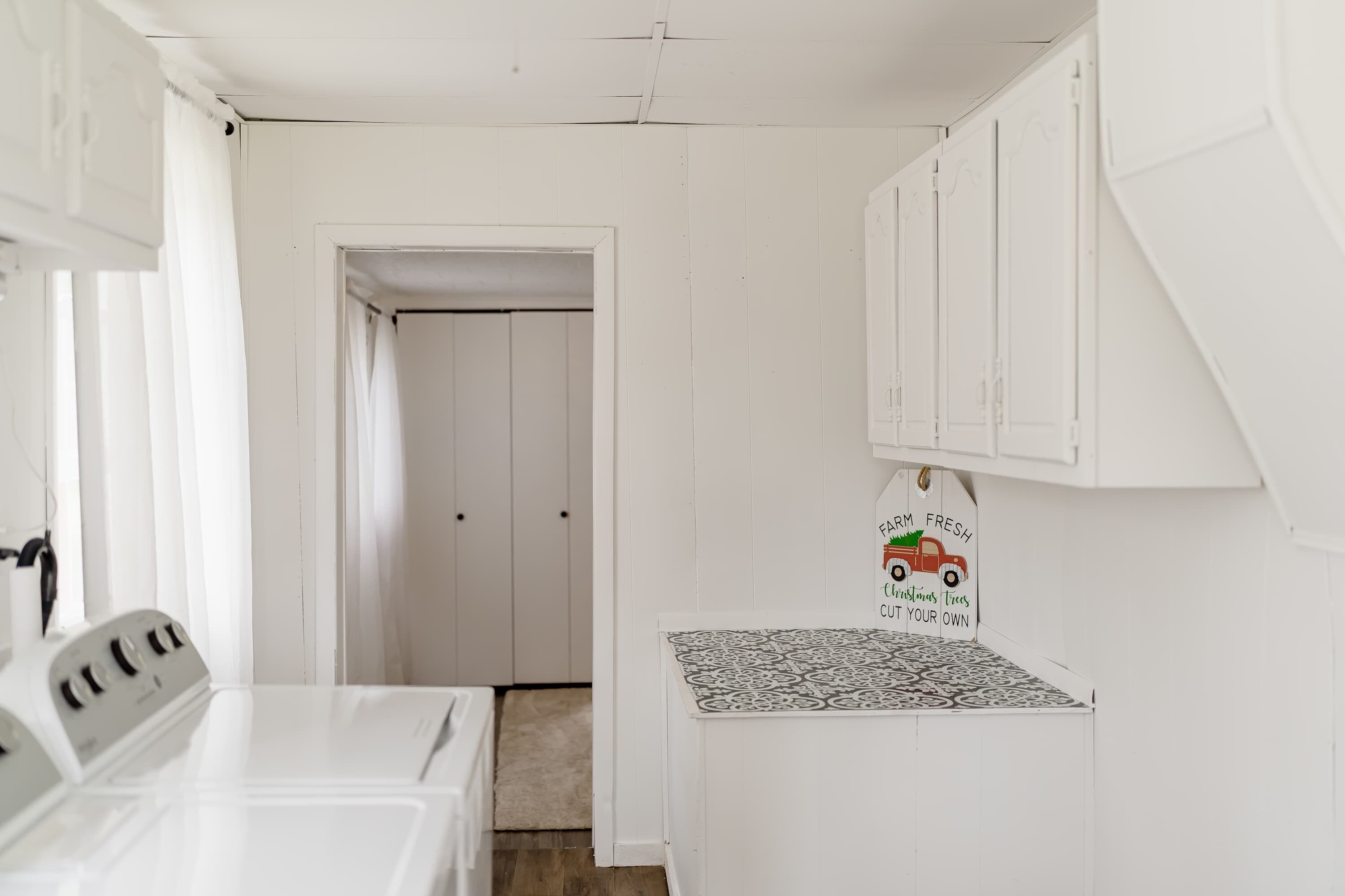 A laundry area with a washing machine, dryer, and a small cabinet with a holiday-themed sign.