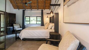 A bedroom with a bed, a chair, a desk, a TV, and a window.