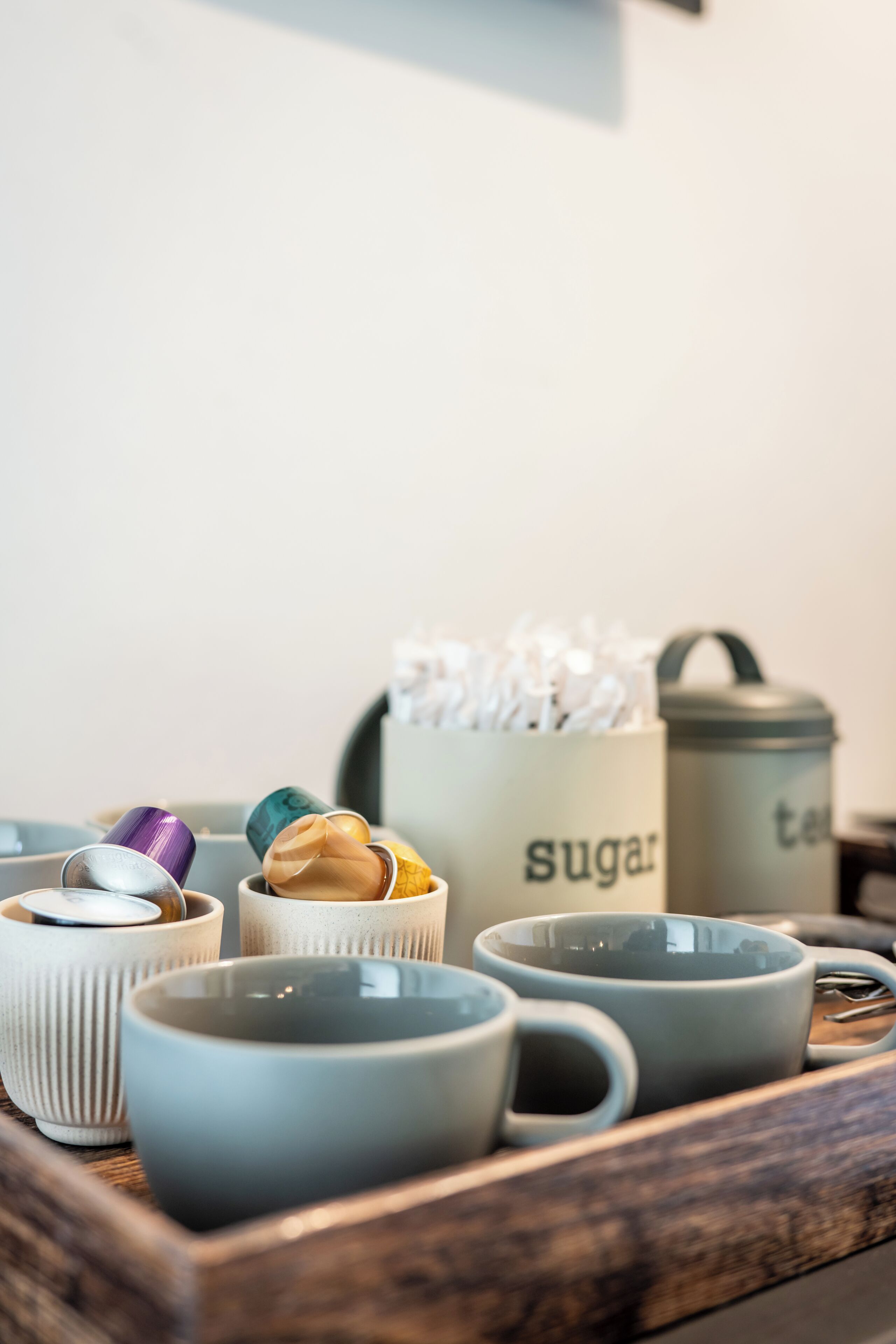 A tray with various kitchenware including cups and a sugar container.
