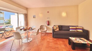 Een woonkamer met een bank, een salontafel en een eethoek met stoelen en een tafel.