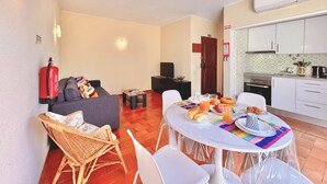 Een ruimtelijk ingerichte leefruimte met een eethoek, kitchenette en een slaapbank.