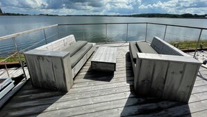 Eine Holzterrasse mit integrierter Sitzgelegenheit und Geländer mit Blick auf ruhiges Wasser.